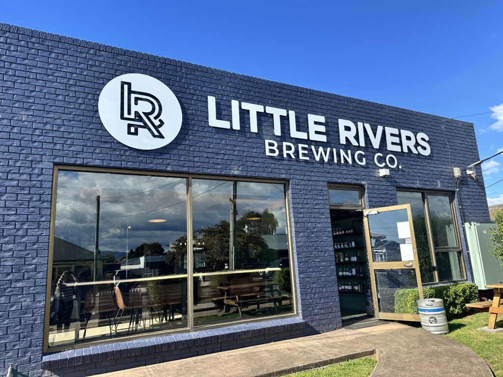 Exterior of Little Rivers Brewing Co. with large windows under a clear blue sky